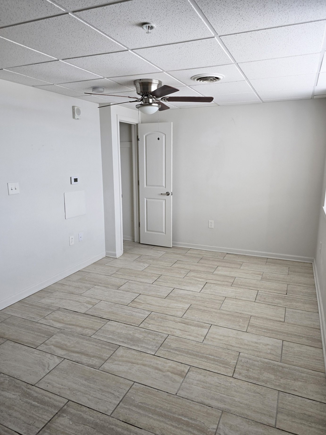 A room with a ceiling fan and a door.